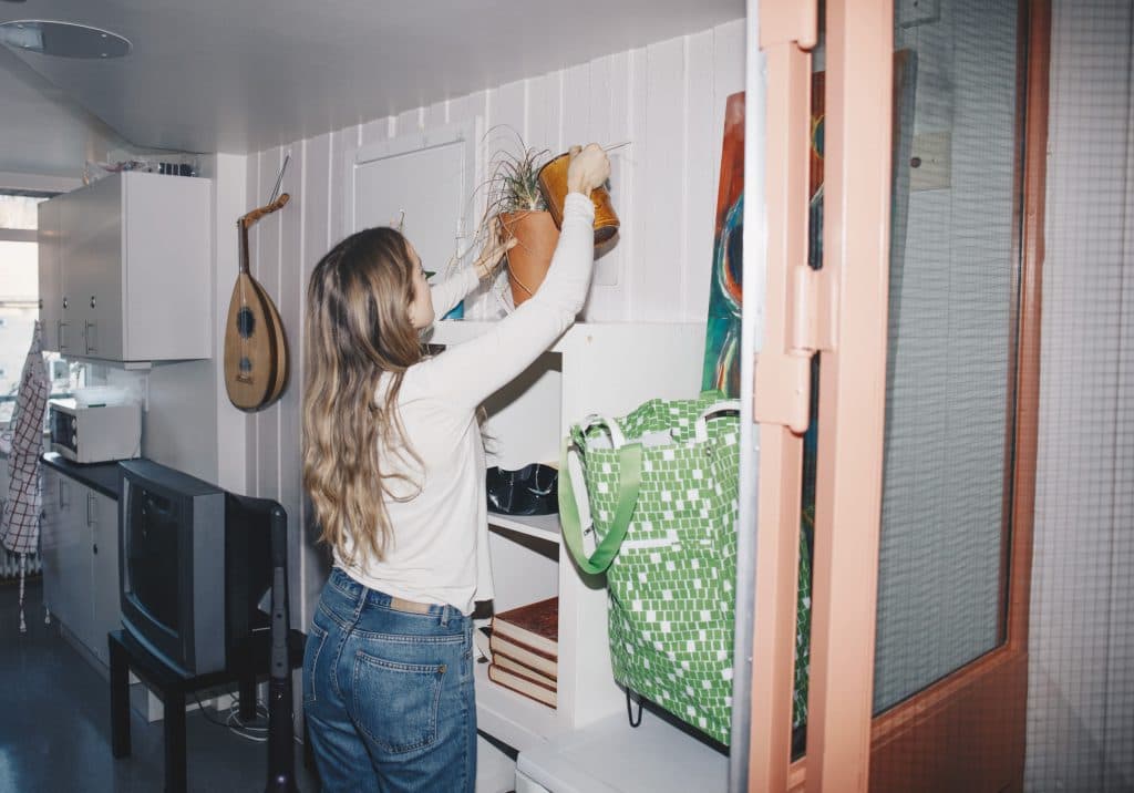 girl watering plants on bookshelf